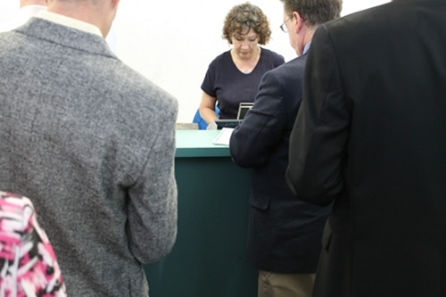 Men purchasing tickets from woman for horse racing.